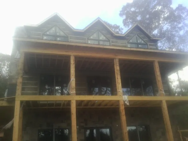 Dormers and porch framing on a large log home under construction — Roof Coating work by our crew in Monett