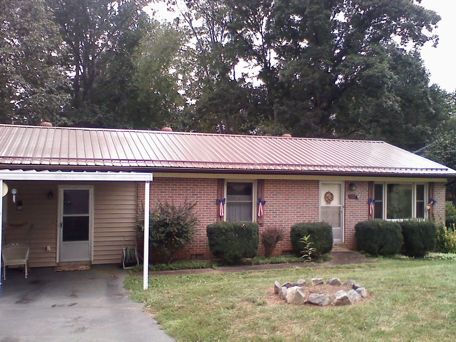 Bronze metal roof and carport on a brick ranch home — Roof Repair work by our crew in Monett