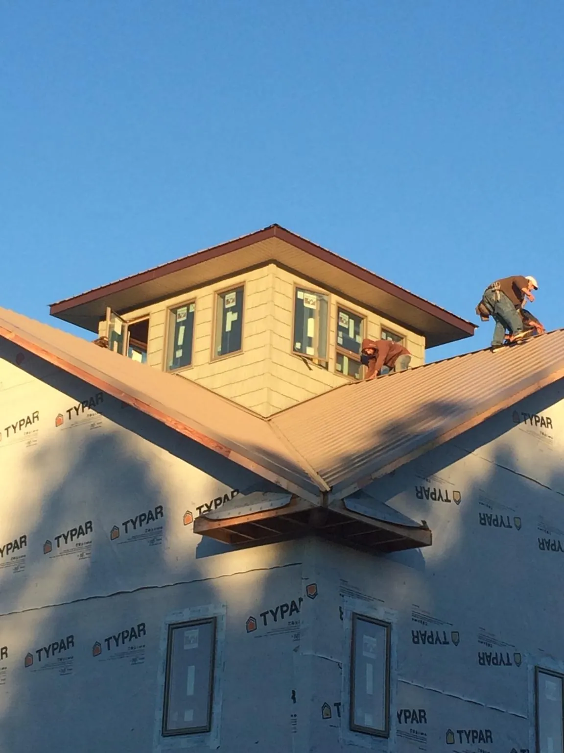 Roofers working around a rooftop cupola on a new metal roof at sunset — Roof Waterproofing in Monett by Roofing Brothers